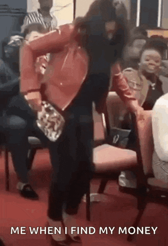a woman in a red jacket is dancing in a crowd of people while holding a purse .