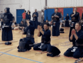 a group of people are kneeling down in a gym and clapping