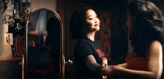 a woman is standing in front of a mirror and looking at herself .