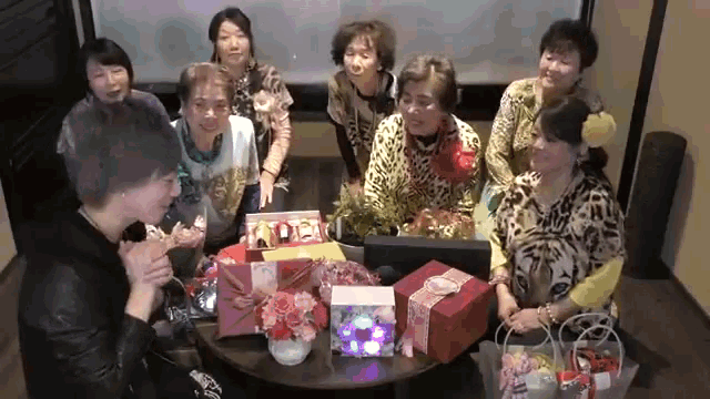a group of women are sitting around a table with gifts and a sign that says ' kobe ' on it
