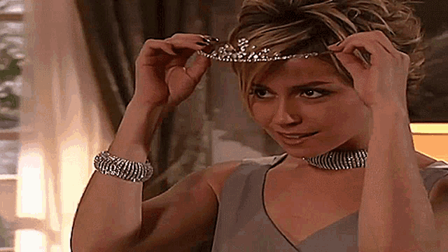 a woman wearing a tiara and a choker is smiling