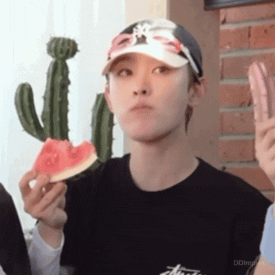 a young man is eating a slice of watermelon while wearing a hat .