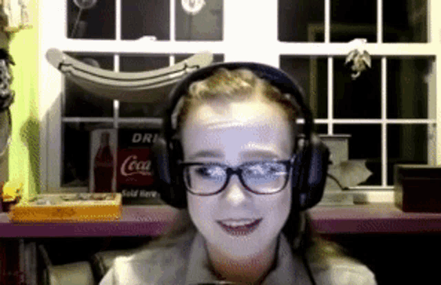 a woman wearing headphones is smiling in front of a window with a coca cola can on it