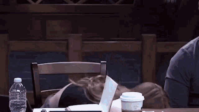a woman is sitting at a table with a cup of coffee and a book .