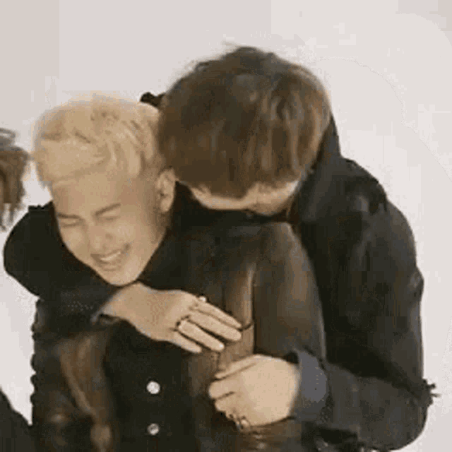 a couple of men are hugging each other and one of them is holding the other 's leg .