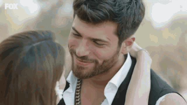 a man with a beard and a woman are kissing each other .