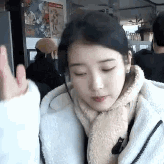 a woman wearing a white jacket and a scarf is giving a high five .