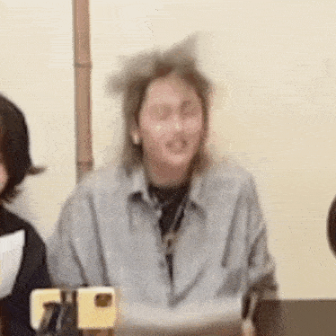 a woman wearing a cat ear headband is sitting at a table holding a cell phone .