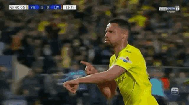 a soccer player in a yellow shirt is pointing at the camera while celebrating a goal .