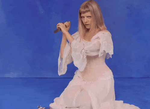 a woman in a white dress is holding a knife in her hand