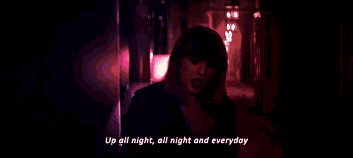 taylor swift is singing a song in a dark room .
