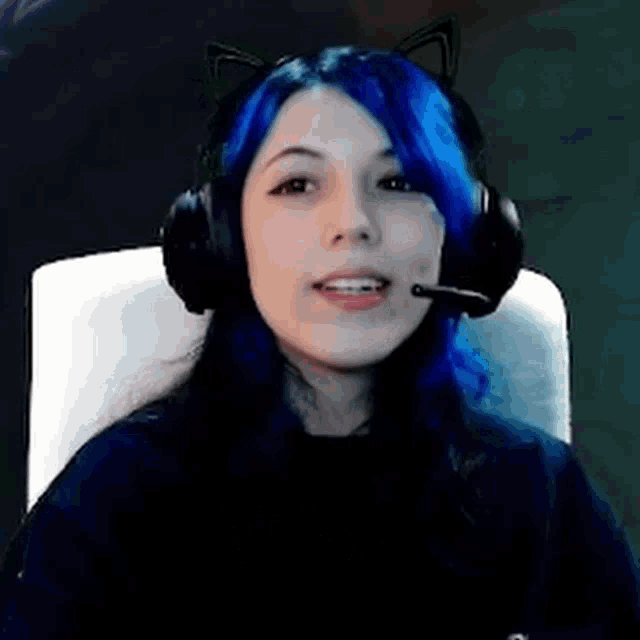 a girl with blue hair and cat ears is wearing headphones and a microphone .