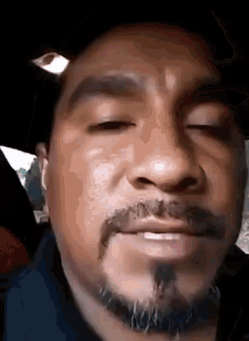 a close up of a man 's face with his eyes closed and a beard .