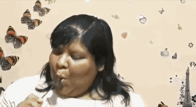 a woman is eating a candy bar with a fork in front of a wall with butterflies on it .