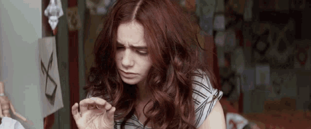 a woman with red hair is looking down at something in her hand