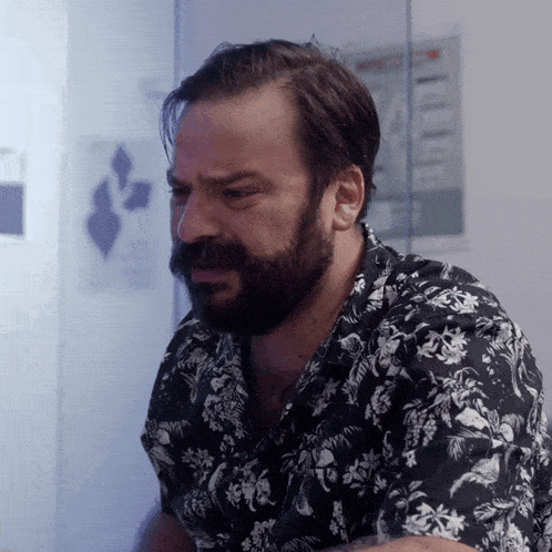 a man with a beard wears a black and white shirt