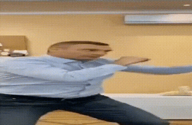 a man in a blue shirt and jeans is doing a karate move .
