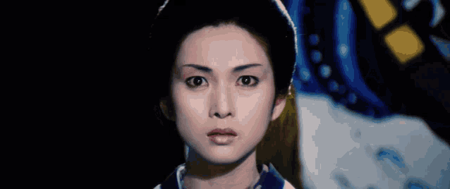 a close up of a woman 's face with a surprised look on her face in a dark room .