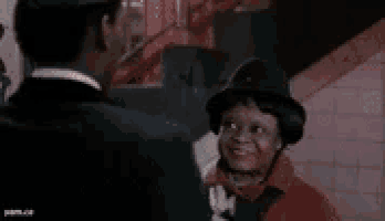 a man in a suit and tie is talking to a woman in a hat