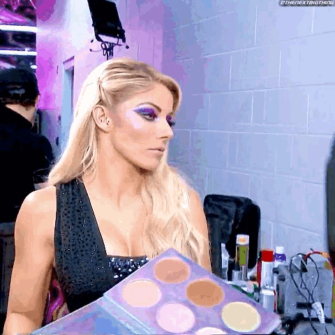 a woman is holding a palette of makeup in her hand