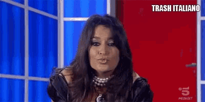 a woman is blowing a kiss in front of a red door and the words trash italiano are on the bottom