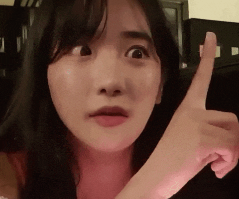 a close up of a woman making a funny face while pointing her finger .