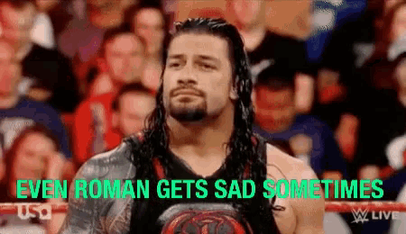a wrestler is standing in front of a crowd with the words `` even roman gets sad sometimes '' written above him .