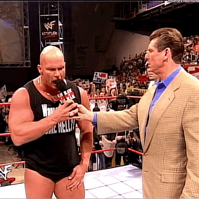 a man in a black tank top with the word hell on it talking into a microphone