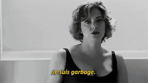 a woman in a black tank top says je suis garbage in yellow letters