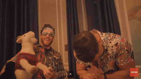 a man holding a stuffed animal next to a man wearing a shirt that says subscribe