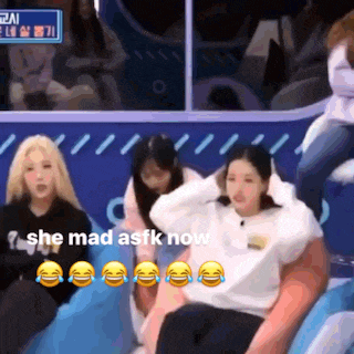 a group of people are sitting in front of a blue sign that says she mad asfk now