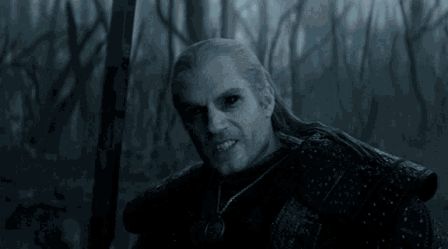 a man with a sword and a necklace is smiling