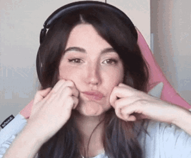 the woman is wearing headphones and making a funny face .