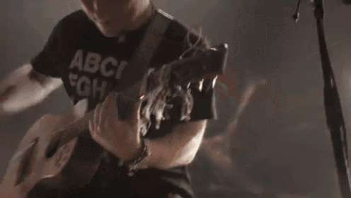 a man is playing a guitar and wearing a shirt that says abc