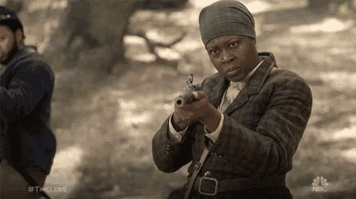 a woman is pointing a gun in a scene from nbc 's timeless series