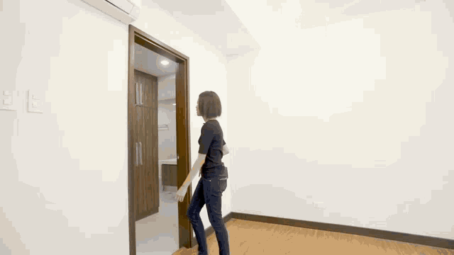 a woman is walking through a doorway in an empty room .