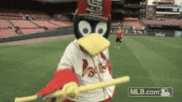 a penguin mascot is holding a baseball bat in a baseball stadium .
