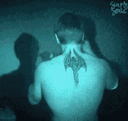 a man with a tattoo on his back is talking on a phone