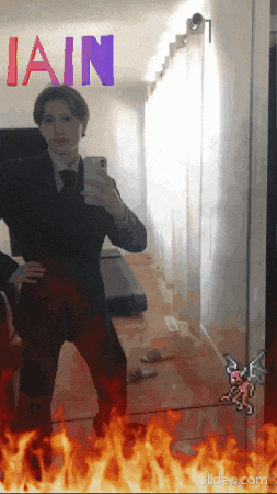 a man in a suit takes a selfie in front of a mirror with the word " iain " above him