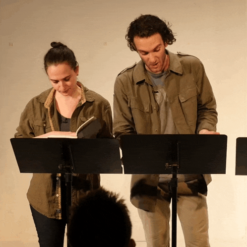 a man and a woman are standing at a podium reading a script
