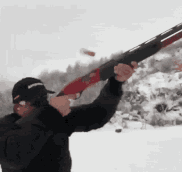 a man in a black hat is holding a shotgun in his hand