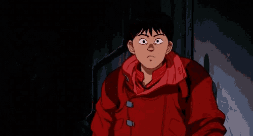 a young boy in a red jacket is standing in a dark room .