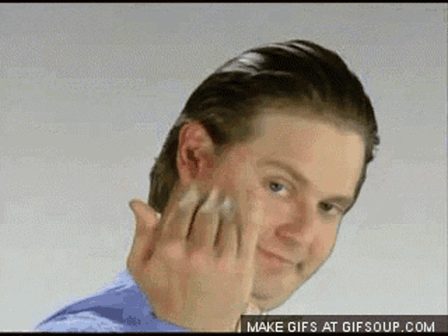a man in a blue shirt is making a funny face with his hands