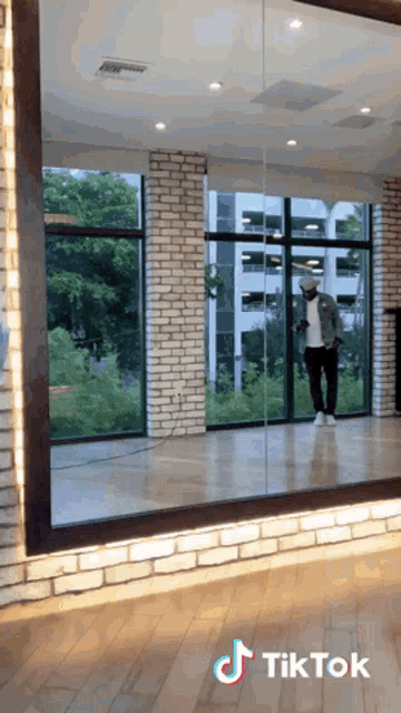 a man is standing in front of a large mirror that says tiktok on the bottom