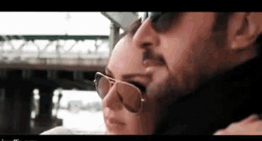 a man and a woman wearing sunglasses are hugging and kissing .