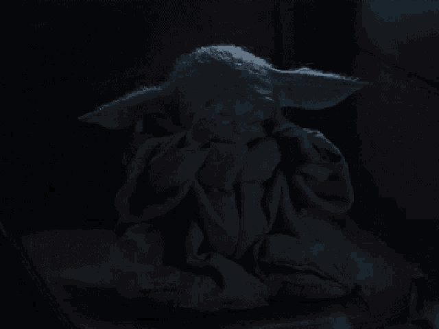 a baby yoda is covering his face with his hands