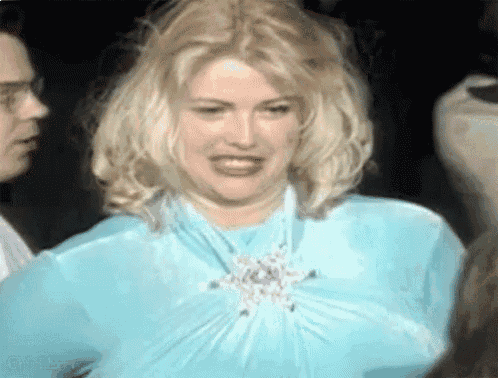 a woman in a blue dress is making a funny face while standing in a crowd .