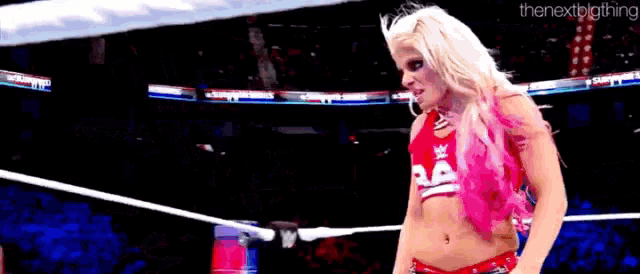 a woman is standing in a wrestling ring wearing a red and white outfit .