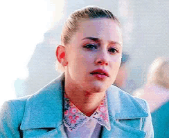 a close up of a woman 's face wearing a blue jacket and a floral shirt .