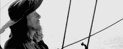 a black and white photo of a bearded man holding a stick .